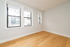 Brighton apartment for rent - an empty room with two windows and a wooden floor
