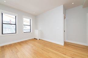 Brighton apartment for rent - an empty living room with a wooden floor and two windows