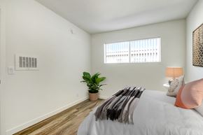 Canoga Park apartment for rent - A bedroom with a bed, a lamp, a plant, and a window.