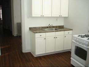 Chicago apartment for rent - a kitchen with white cabinets and a sink and a stove