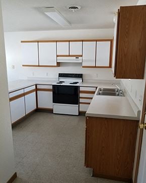 Luverne townhouse for rent - an empty kitchen with white cabinets and a black stove