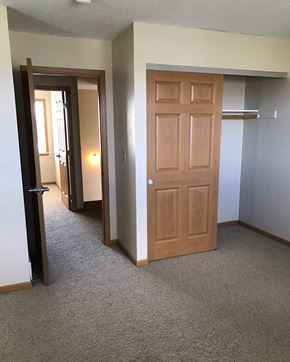 Pipestone apartment for rent - a bedroom door and a hallway with a closet and a mirror