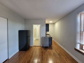 Chicago apartment for rent - a living room with a radiator and a hallway to a kitchen
