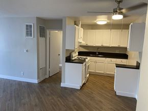 Los Angeles apartment for rent - an empty kitchen with white cabinets and a black counter top