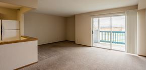 Ada apartment for rent - an empty living room with a sliding glass door to a balcony
