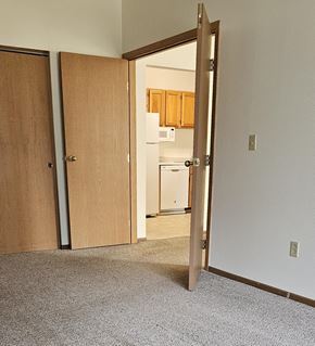 Erskine apartment for rent - A room with a carpeted floor and a white wall with a doorway leading to a kitchen.