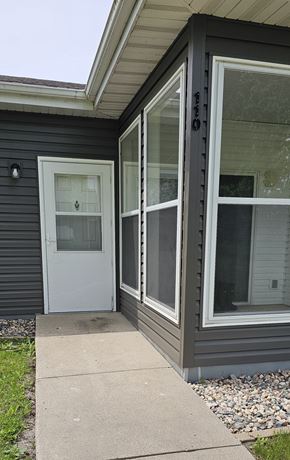 Fosston apartment for rent - A grey house with a white door and windows.