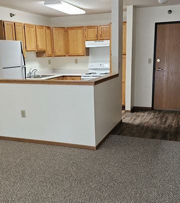 Fosston apartment for rent - A kitchen with white countertops and wooden cabinets.