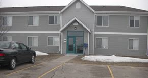 Thief River Falls townhouse for rent - a gray building with a blue door and a car parked outside
