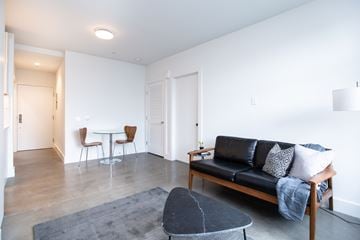 San Francisco apartment for rent - A living room with a black couch and a grey rug.