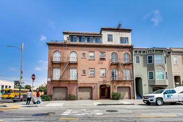 San Francisco apartment for rent - A red brick building with a white car parked in front of it.