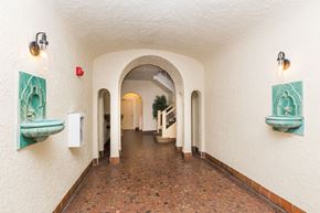 San Francisco apartment for rent - A long corridor with arches and a red fire alarm on the wall.