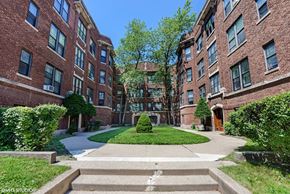 Evanston apartment for rent - a walkway in front of a brick building with a green courtyard