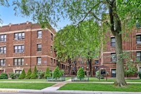 Chicago apartment for rent - exterior view of a red brick building with green grass and trees