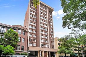 Chicago apartment for rent - a tall brick building with many windows and a street with trees