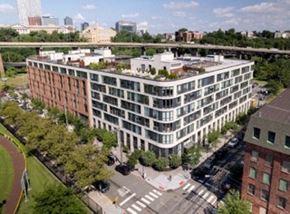 Jersey City apartment for rent - A large white building with a lot of windows is surrounded by trees.