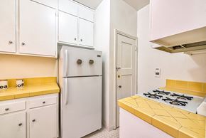 Hollywood apartment for rent - a kitchen with white cabinets and a yellow counter top and a refrigerator