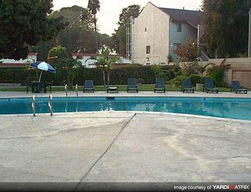 Anaheim apartment for rent - a swimming pool with four chairs and an umbrella