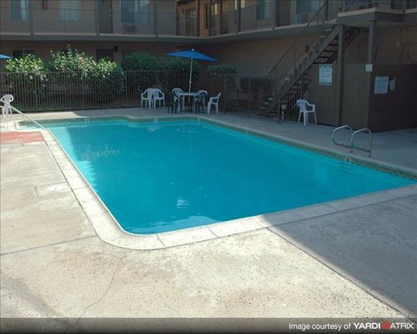 Anaheim apartment for rent - a blue swimming pool in front of a building