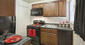 Rahway apartment for rent - a kitchen with black appliances and wooden cabinets and a sink