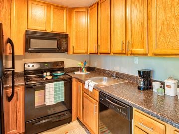 Hampton apartment for rent - A kitchen with wooden cabinets and black appliances.