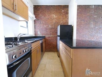 New York apartment for rent - a kitchen with an exposed brick wall and black counter tops