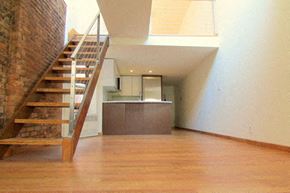 New York apartment for rent - an empty living room with a staircase and a kitchen