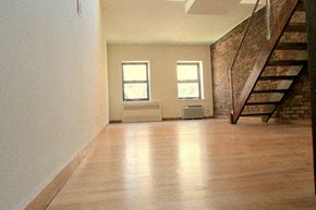 New York apartment for rent - an empty living room with a staircase and a wood floor