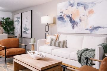 Las Vegas apartment for rent - A living room with a white couch, a wooden coffee table, and a large abstract painting on the wall.