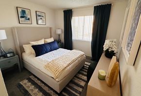 Las Vegas apartment for rent - A bedroom with a large bed and a nightstand with a lamp.