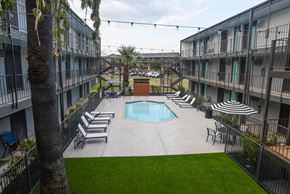 Austin apartment for rent - A pool surrounded by lounge chairs and umbrellas in a courtyard.