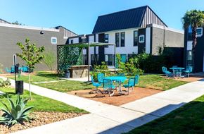 Austin apartment for rent - A sunny day at a modern building with a green lawn and blue chairs.