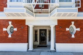 San Francisco apartment for rent - A red brick building with a white balcony and two white columns on either side of the door.
