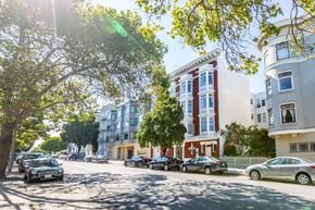 San Francisco apartment for rent - Cars parked on a street with trees and buildings on either side.