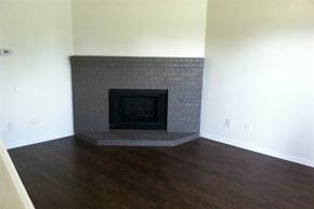 Denton townhouse for rent - a living room with a stone fireplace and a wooden floor