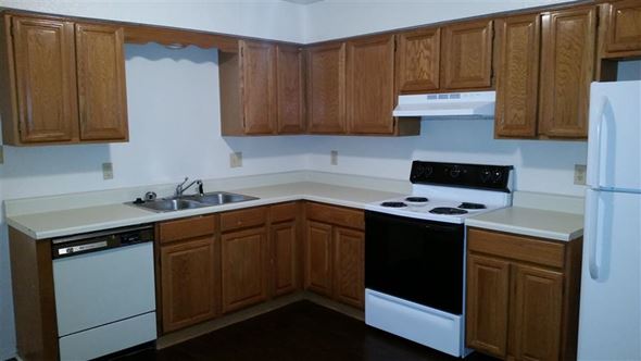 Denton townhouse for rent - a kitchen with white appliances and wooden cabinets