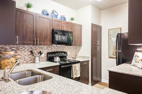 Austin apartment for rent - North Austin, TX Apartments - Kitchen With Granite-Style Countertops, Wood-Style Cabinets, Modern Appliances, Microwave, Oven, Dual Sink, Fridge, Tile Back-Splash, And Wood-Style Flooring.