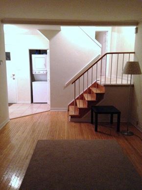 Toronto apartment for rent - A hallway with a staircase and a table with a lamp.
