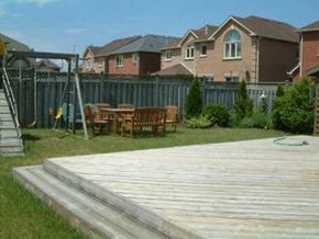 Markham apartment for rent - A wooden deck with a table and chairs is in the foreground of a residential area.