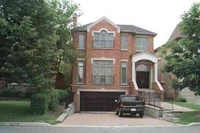 Toronto apartment for rent - A black car is parked in front of a red brick house.