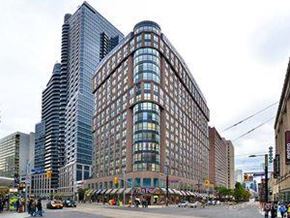 Toronto apartment for rent - A large building with many windows is in the middle of a city street.