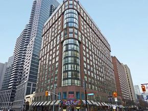 Toronto apartment for rent - A tall building with a curved glass facade stands next to a shorter building with a brick facade.