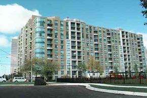 Toronto apartment for rent - A large building with many windows is surrounded by a black fence.