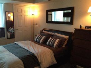 Toronto apartment for rent - A bedroom with a bed, nightstand, and lamp.