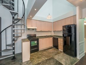 Toronto apartment for rent - A kitchen with a black refrigerator and a spiral staircase.
