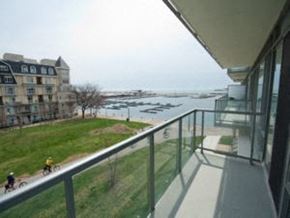 Toronto apartment for rent - A balcony overlooks a grassy area and a body of water with boats.
