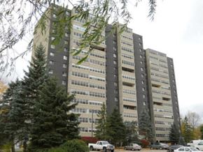 Toronto apartment for rent - A tall building with many windows and cars parked in front.
