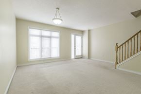 Waterloo apartment for rent - A spacious room with a carpeted floor, a staircase with wooden railings, and two windows with blinds.