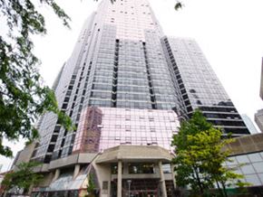 Toronto apartment for rent - A tall building with a glass facade stands in front of a smaller building.