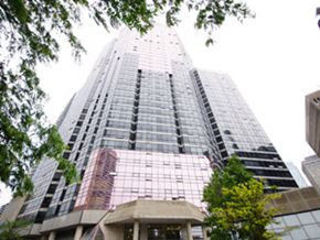 Toronto apartment for rent - A tall building with a glass facade stands between two trees.